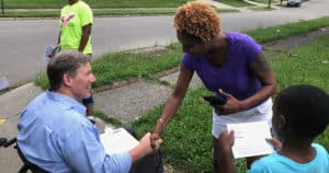 Wheelchair user shaking hands with voter, campaign training to disabled candidates
