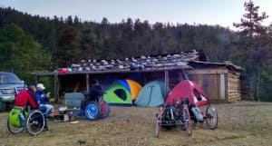 A group of backpacking handcyclists makes camp.
