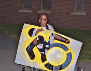 Kamisha is one of many young wheelchair users around the nation who are excitedly laying down stencils from the Accessible Icon Project and replacing the old icon with the new.