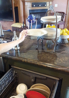 The trick to a fully-functional kitchen is to ensure the areas most used are at an ideal height.  Here, the author demonstrates a plate rack in close proximity to the dishwasher, a pull-out cutting drawer and a lap-high oven — and she doesn’t have to overreach for anything. 