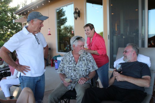Three men chat in foreground with woman walking past in background