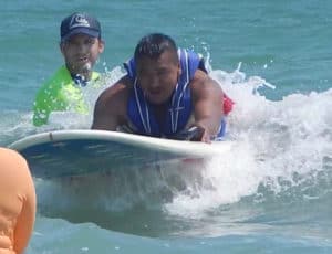 Jose Solorio gets pushed into a wave on a beginner, solo prone surfboard.