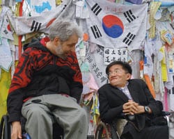 Rains and a fellow advocate sit by the wall that marks the beginning of a no man's land between North and South Korea.