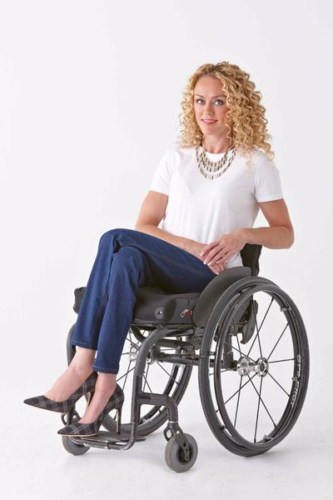 Woman in wheelchair wearing IZ Adaptive clothing blue jeans and white shirt 