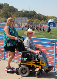 Judi Chapman demonstrates the Care E On companion platform on the back of husband Byron's wheelchair.