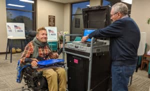 shows Tucker Cassidy in power wheelchair to illustrate disabled voting practices.