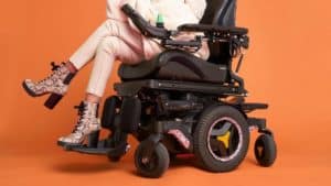 Power wheelchair with LUCI mounted on it and woman sitting with legs crossed in it