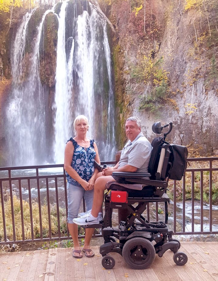 Jeff Kletzmayer sitting in powerchair in front of a waterfall