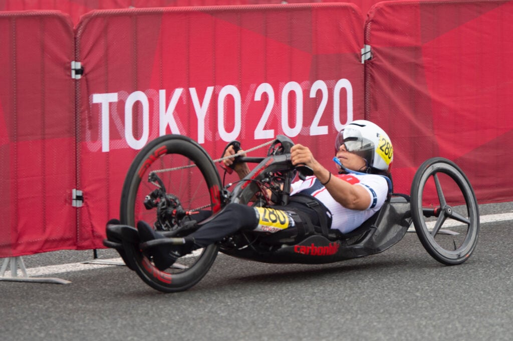 Alicia Dana rides her handcycle past a Tokyo 2020 banner.