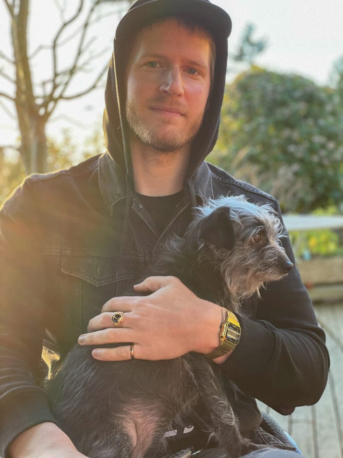 Eric holding a small shaggy dog on his lap.