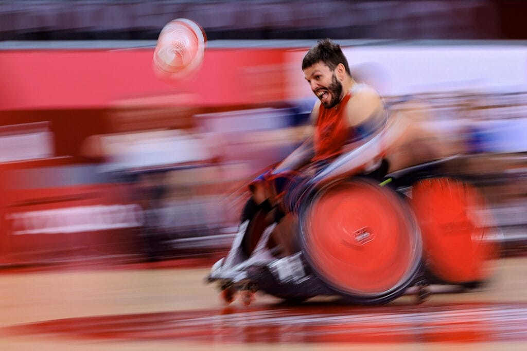Blurred image of paralymic athlete in sports chair going for the ball
