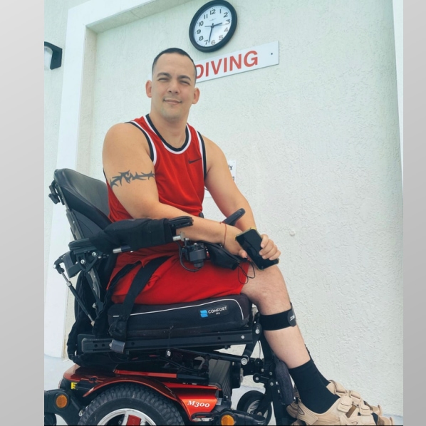 Arnedo in powerchair wearing red tank top and shorts