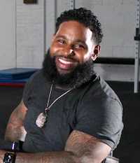 Wesley Hamilton, a Black man in his mid-30s with a dark beard and mustache and a smile in his eyes.  He is wearing a black sweatshirt and a silver chain around his neck.