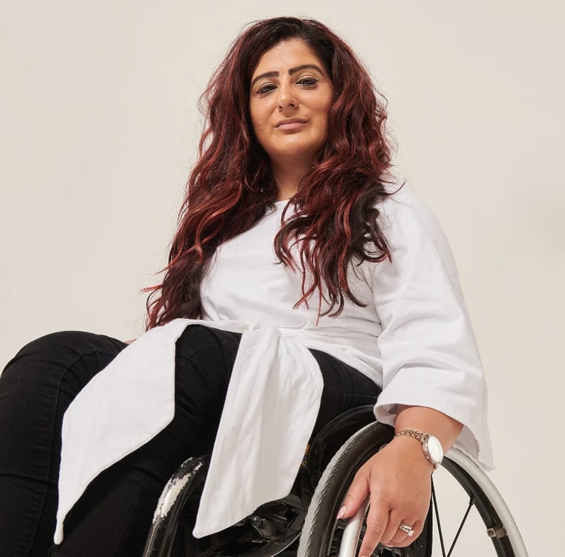 woman in wheelchair wearing black pants and a white wrap-top