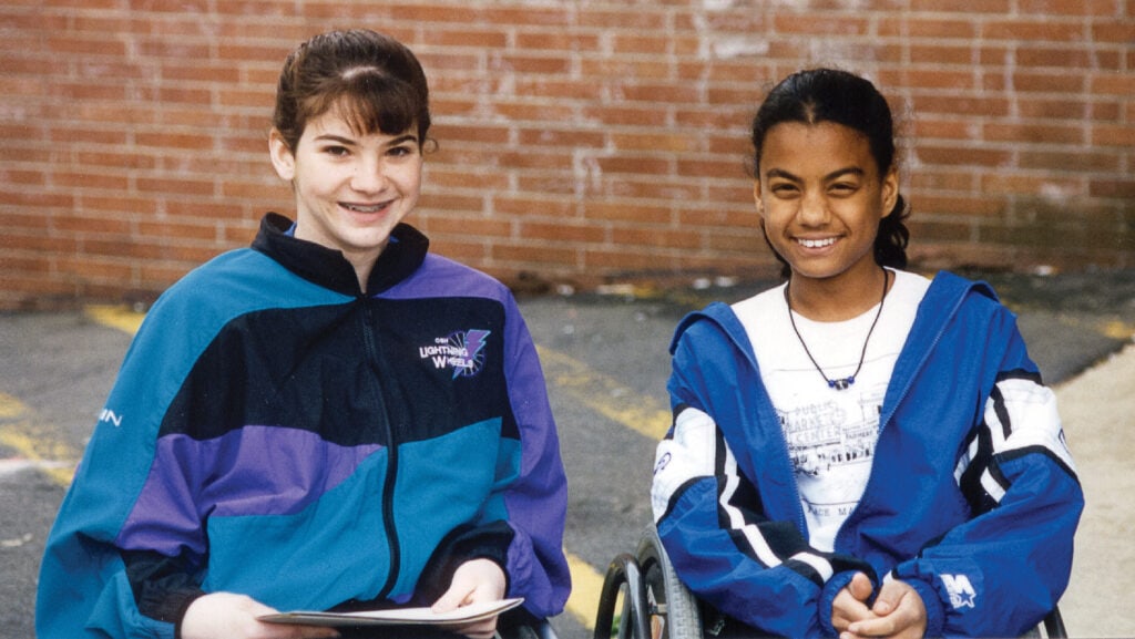 two young girls sitting nect to each other, one in a wheelchair