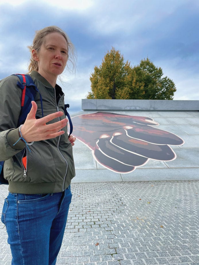 Jennilie Brewster standing next to mural of black fist  