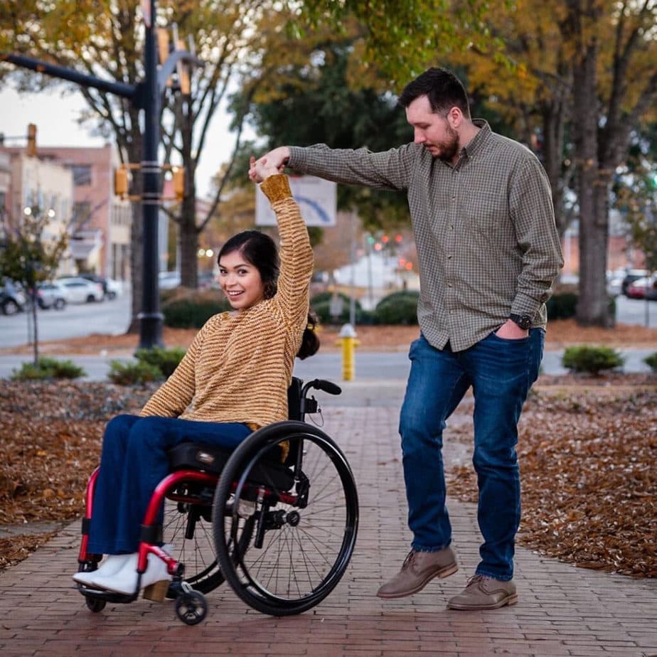 man holding woman on wheelchair's hand as if dancing