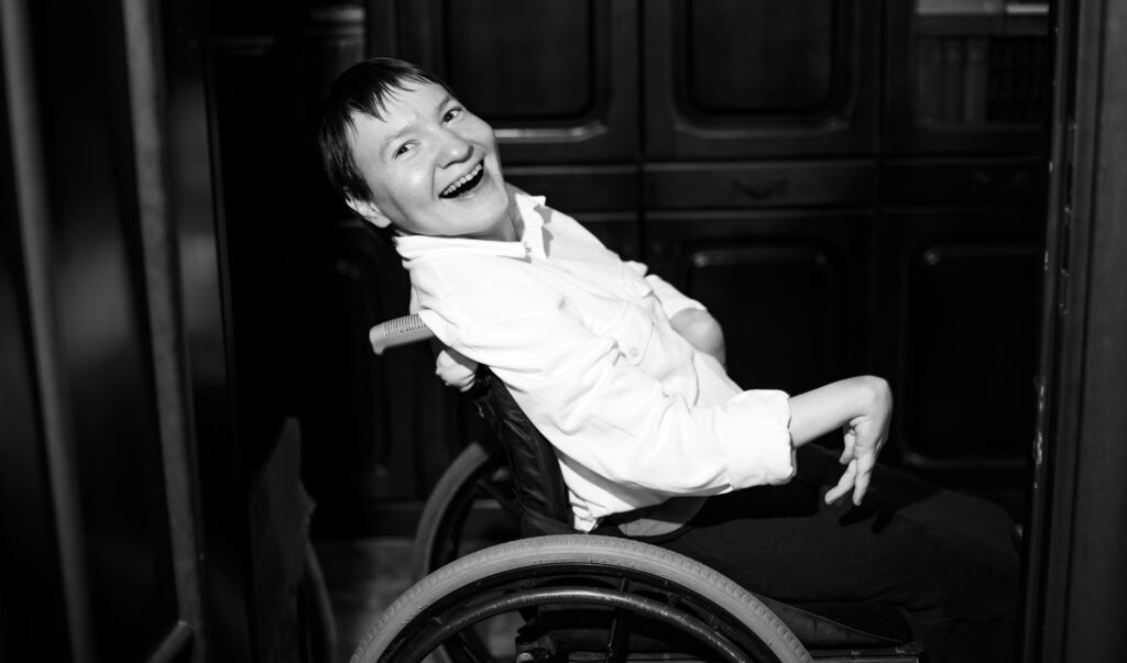sideview of Oksana sitting in wheelchair laughing