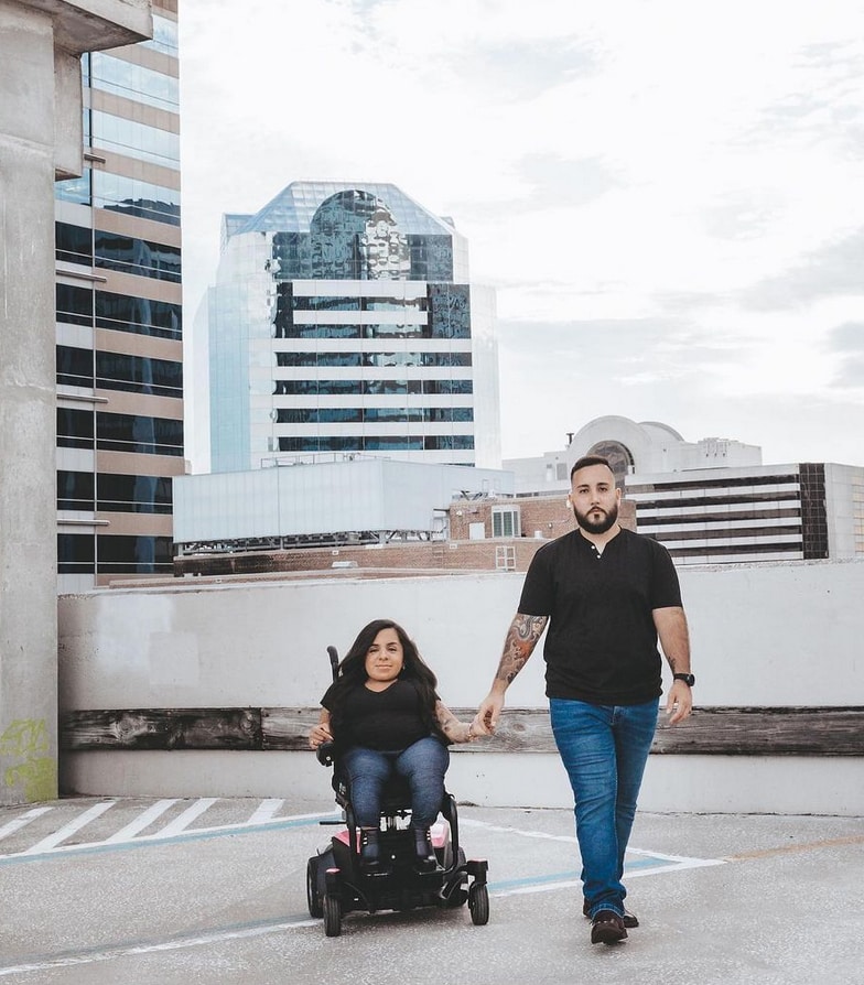 man walking across a roof top with woman in powerchair