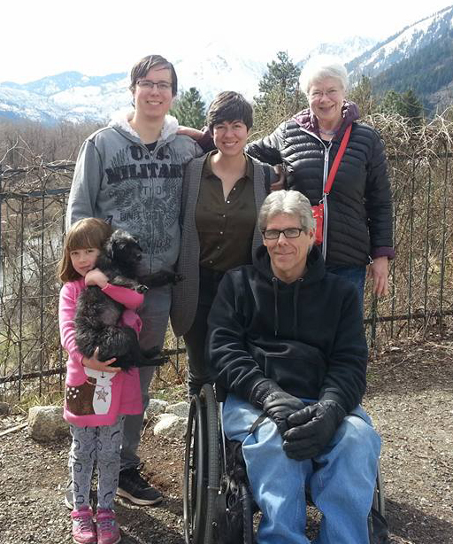 Man sitting in wheelchair outdoors surrounded by family members