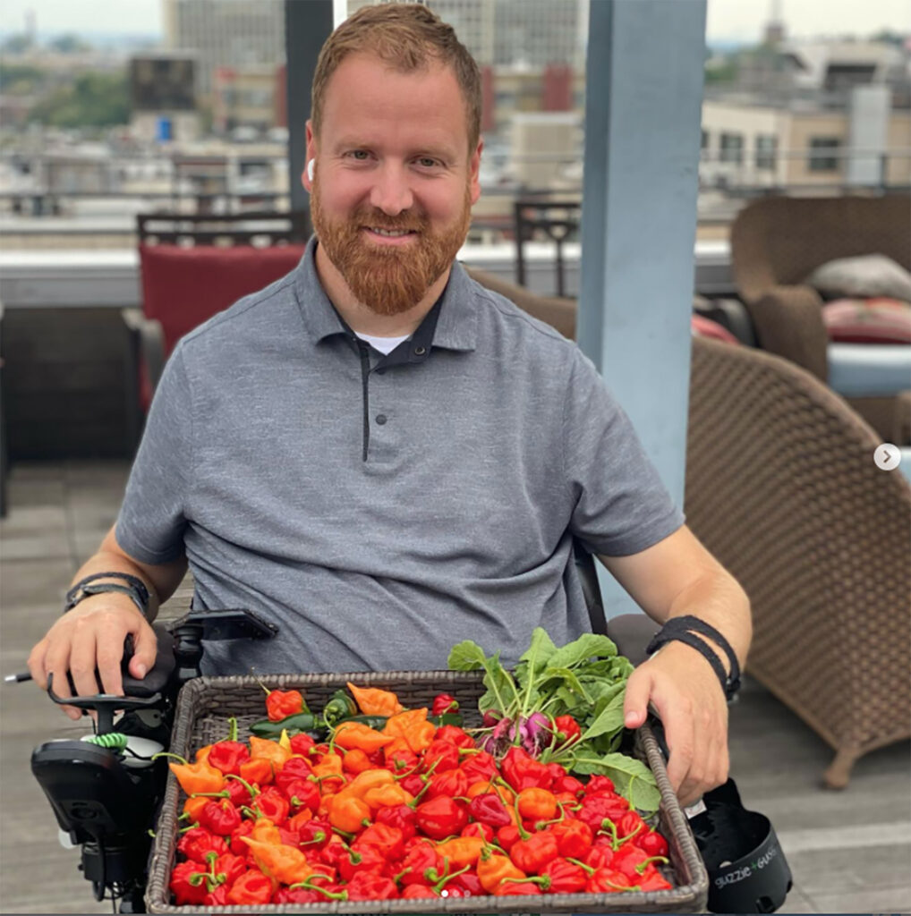 man in wheelchair with tray of fresh peppers in his lap