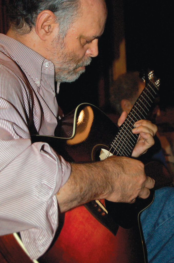 close up of man playing accoustic guitar