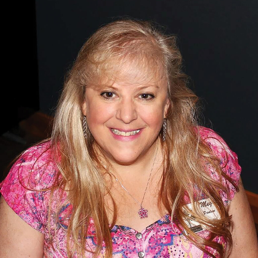close up of blonde woman in pink shirt smiling 