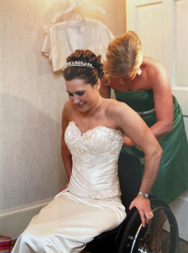 woman in wheelchair getting zipped up in her wedding dress
