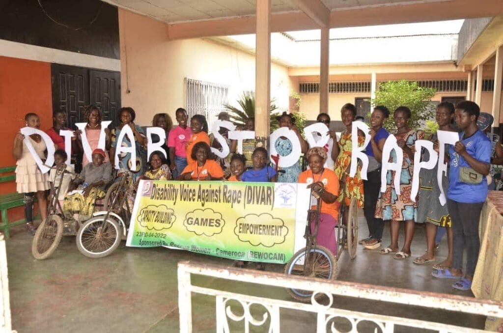 Group of women, front row using tri-cycle mobility devices and holding banner that reads "Disability Voice Against Rape"