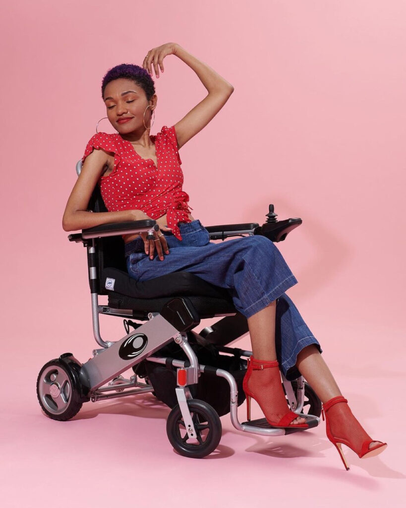Spencer sitting in wheelchair modeling red high-heel shoes