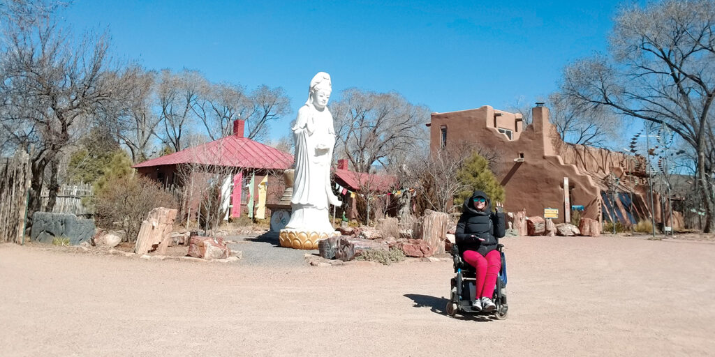 woman in wheelchair in front of old Spanish buildings in Santa Fe 