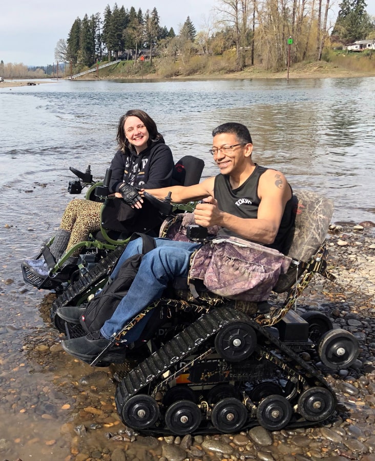 man and woman in track wheekchairs by a lake