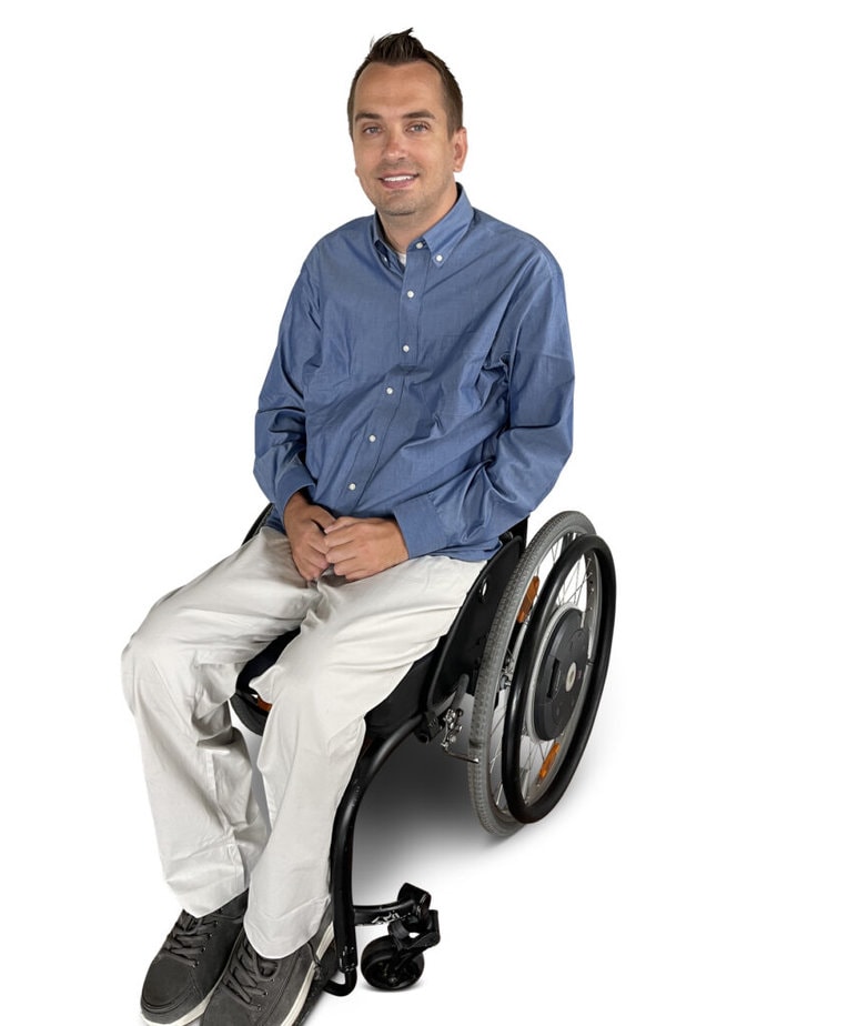 Man in wheelchair modeling blue button down shirt and khaki pants