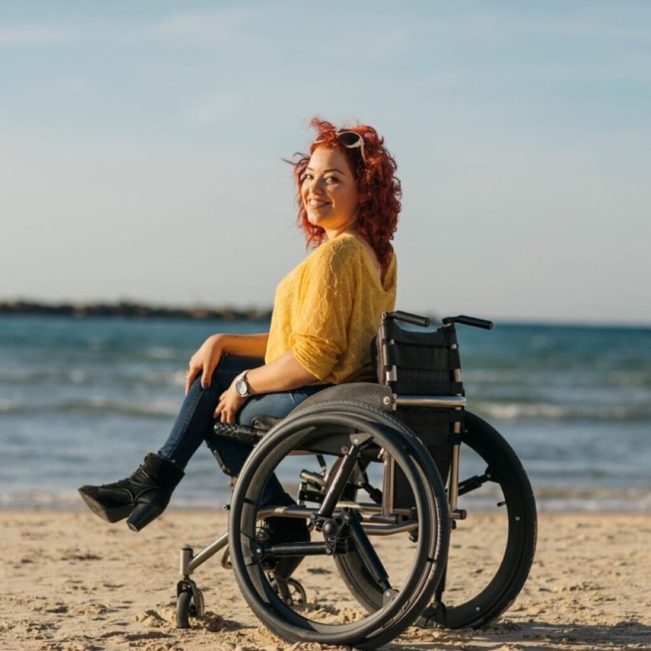 woman sitting on beach in wheelchair with SoftWheels wheels.