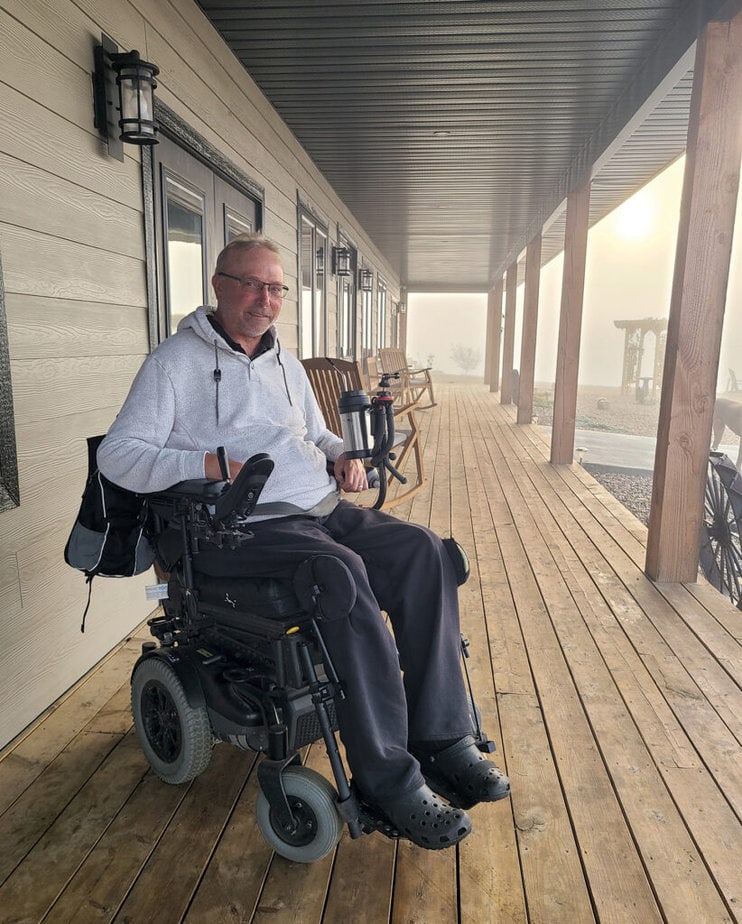 man in powerchair on covered porch 