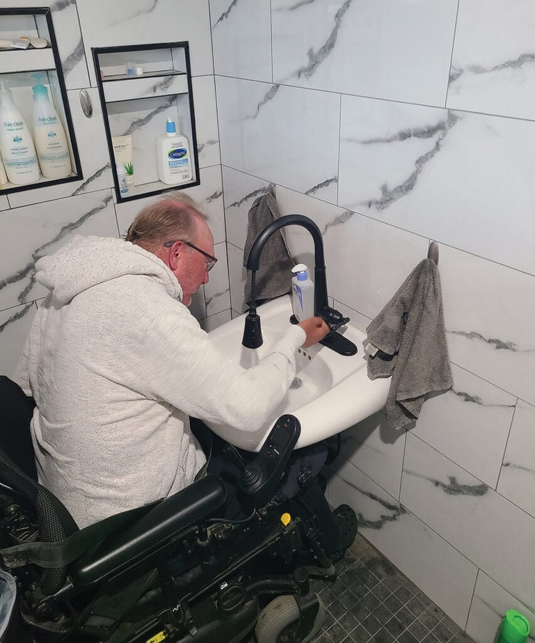 man in powerchair using accessible height bath sink