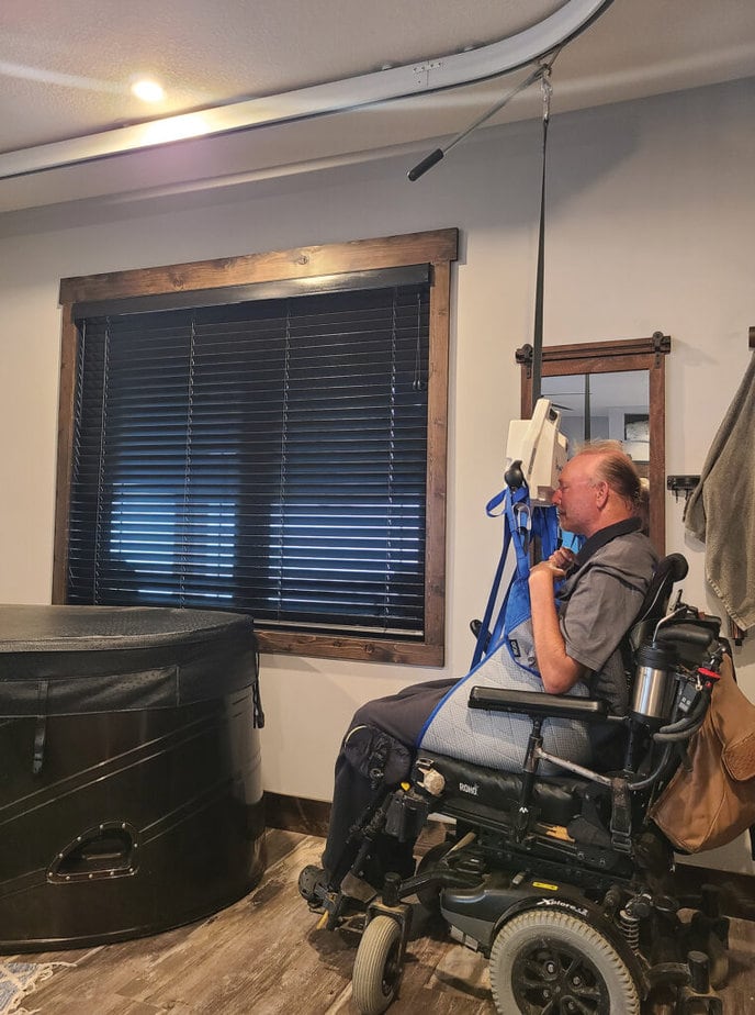 man in powerchair using a ceiling lift by indoor hot tub