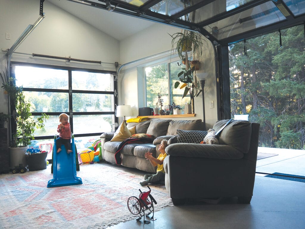 children playing in open living room that has glass garage doors installed in walls