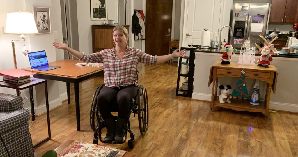 woman in wheelchair with arms open wide displaying inside of her home