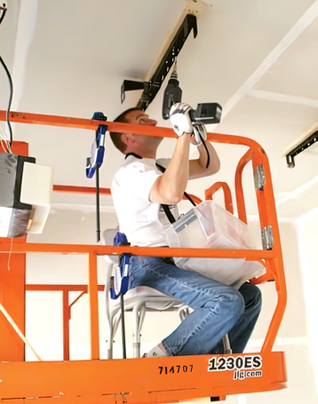 man on lift installing brackets on ceiling