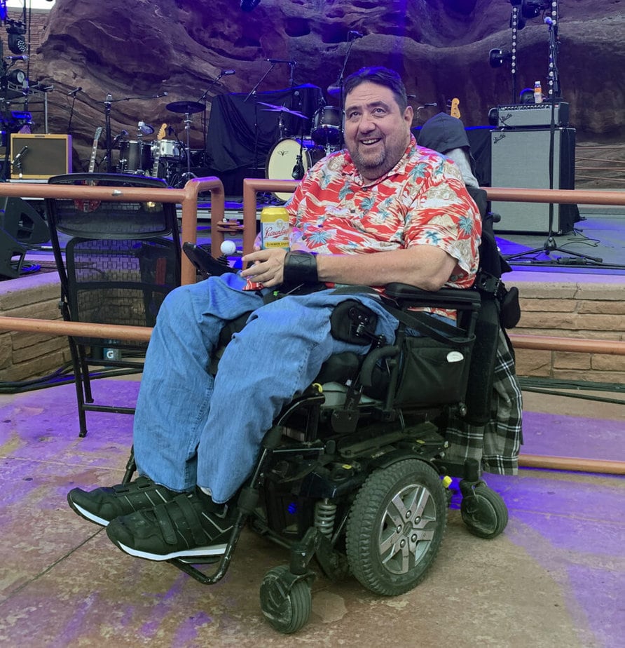 man in powerchair with amphitheater stage in background