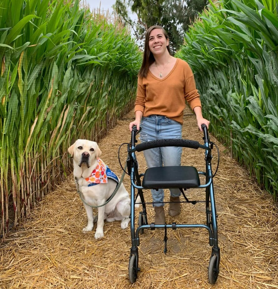 woman standing next to walker with a dog by her side
