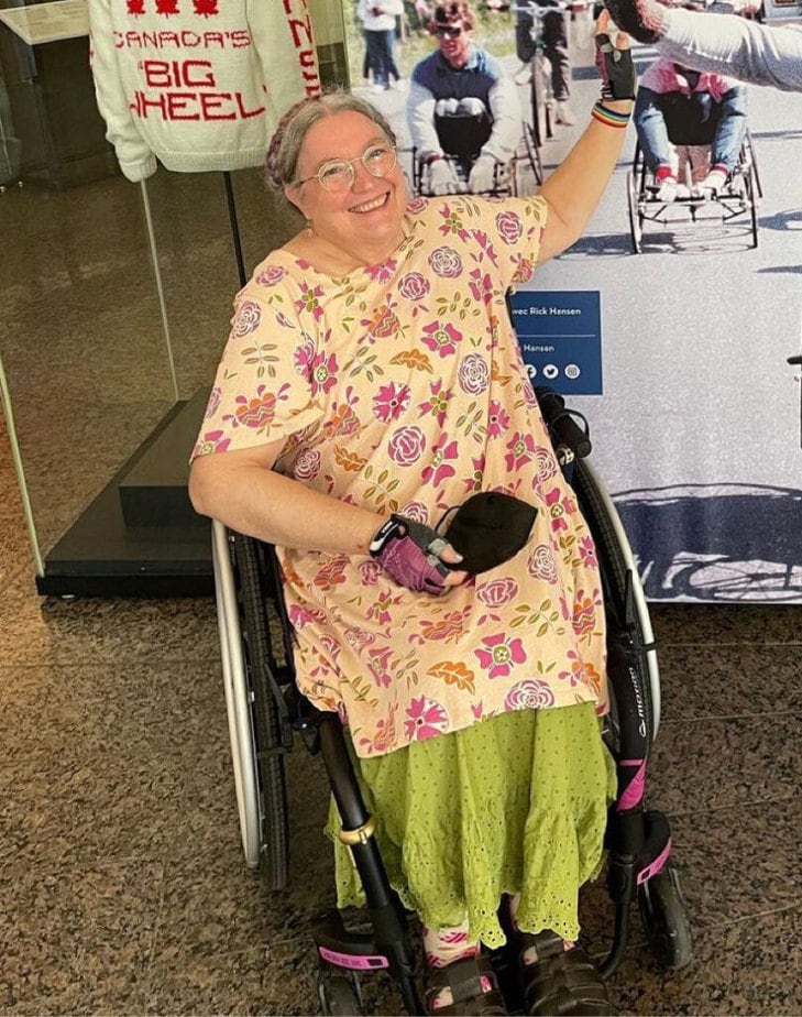 smiling woman in wheelchair giving someone off camera a high-five