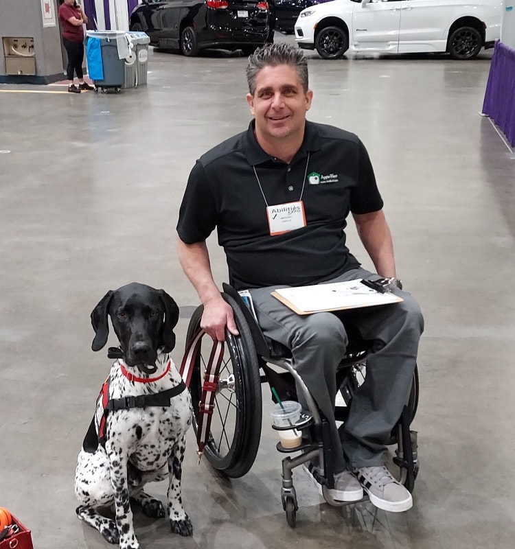 dog sitting next to man in wheelchair