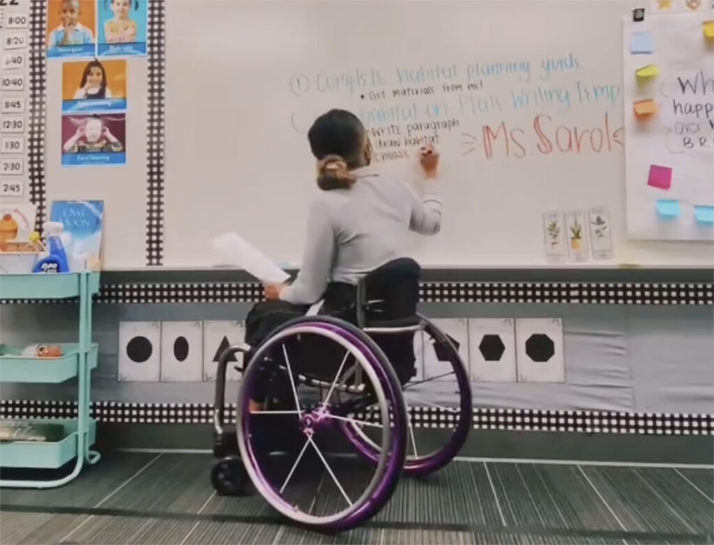 wheelchair-using teacher writing on board