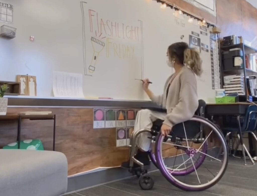 wheelchair-using teacher writing on board