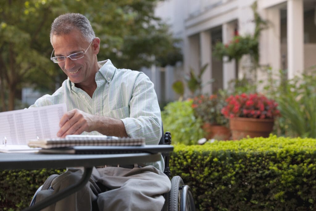 Businessman with spinal cord injury working on documents at a cafe