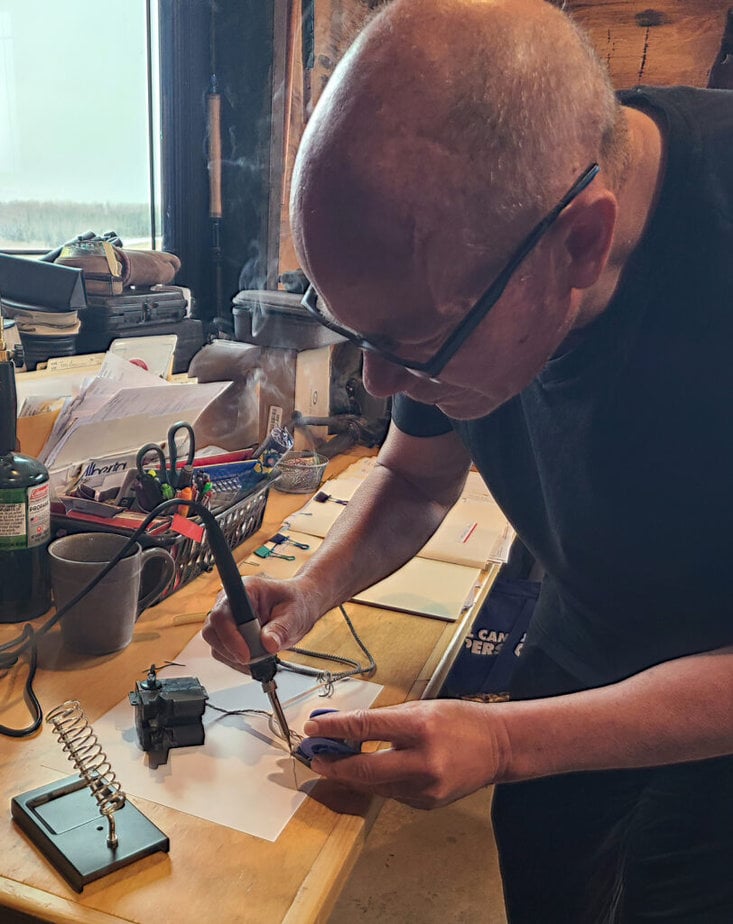 man standing over a counter soldering wires