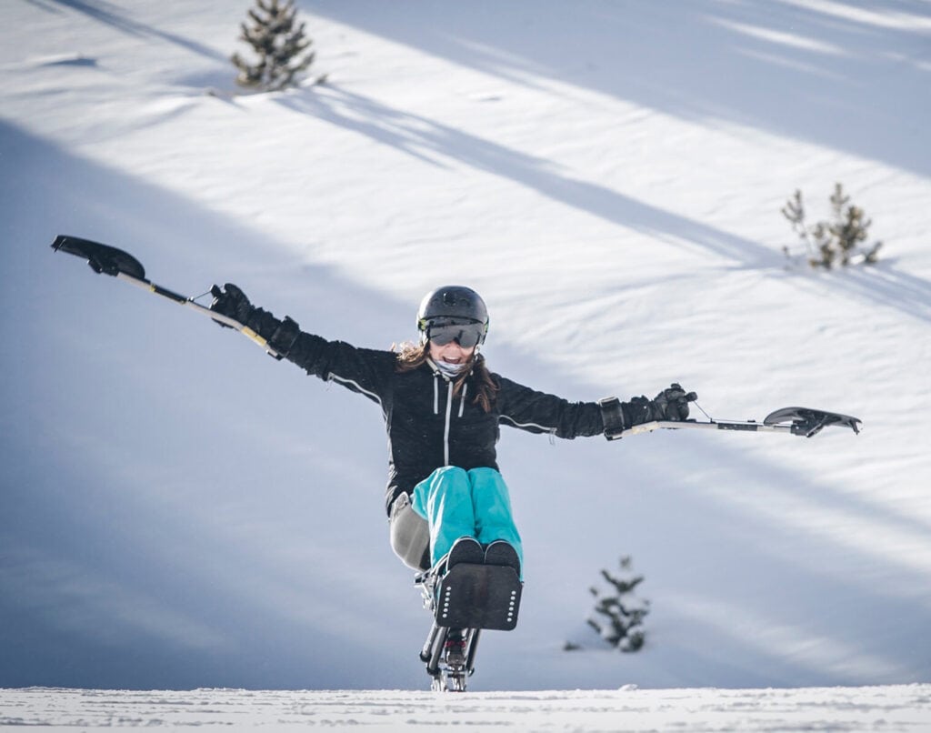 woman skiing on monoski with arms wide open
