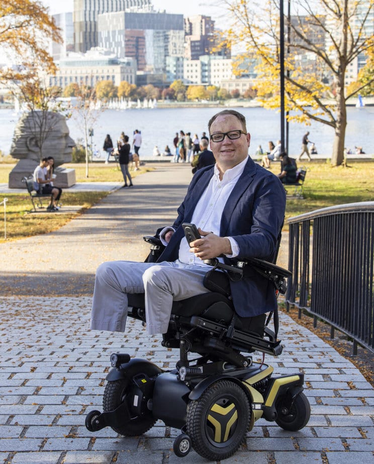 man in powerchair on brick path in city park 